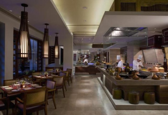 Dining at The Peninsula Manila, a gay-friendly hotel. Restaurant interior with chefs preparing food. Fine dining experience in Makati.