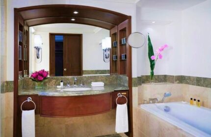 Bathroom at The Peninsula Manila, a gay-friendly hotel. Features a marble countertop, vanity mirror, bathtub, & upscale amenities.