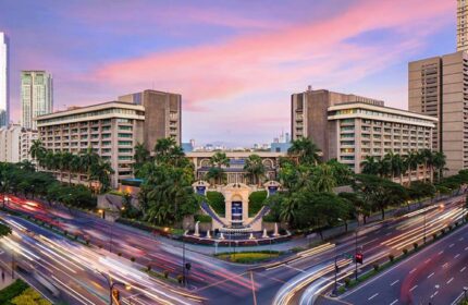 The Peninsula Manila, a gay-friendly hotel. Exterior view at dusk with city traffic. An ideal choice for gay travelers in Manila.