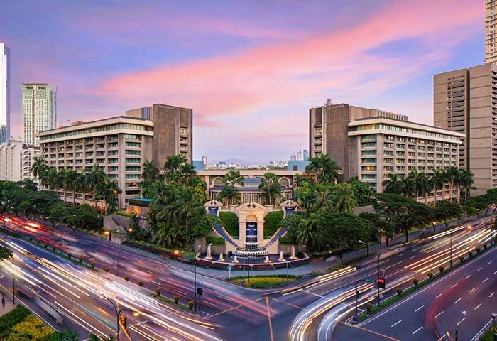 The Peninsula Manila, a gay-friendly hotel. Exterior view at dusk with city traffic. An ideal choice for gay travelers in Manila.
