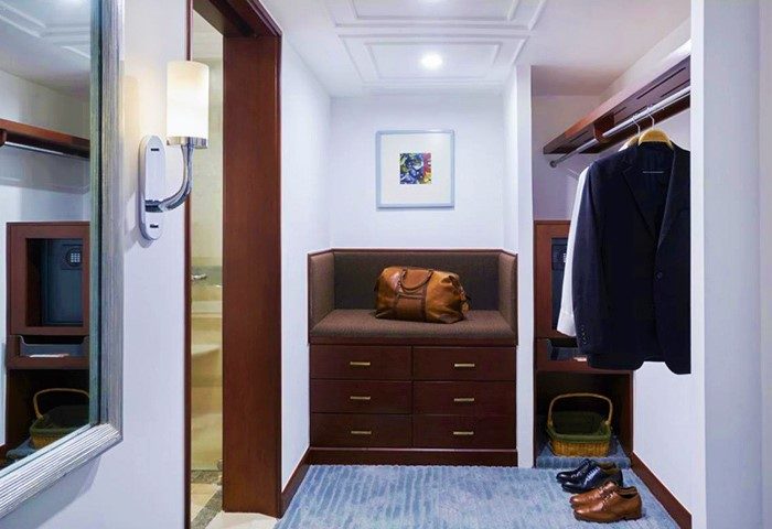 Closet area at The Peninsula Manila, a gay-friendly hotel. Features luggage, drawers, hanging clothes, and shoes. Great for gay travel.
