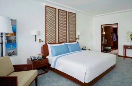 The Peninsula Manila gay-friendly hotel room. Modern design with a large bed, blue accents, and a walk-in closet, ideal for gay travelers.
