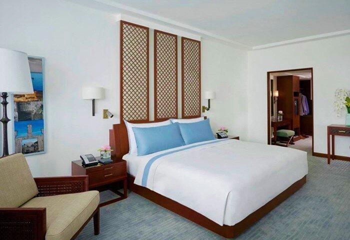 The Peninsula Manila gay-friendly hotel room. Modern design with a large bed, blue accents, and a walk-in closet, ideal for gay travelers.
