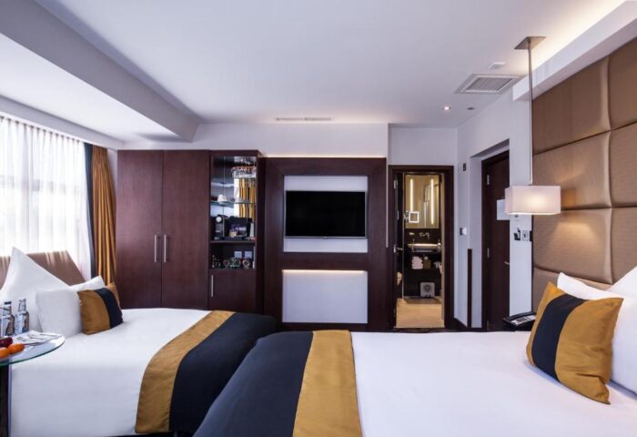 Gay-friendly hotel The Piccadilly London West End room. Modern design, two beds, TV, wardrobe, and bathroom. Ideal for gay travelers in London.