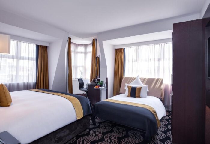 The Piccadilly London West End gay-friendly hotel room. Two twin beds, desk, and large windows. Upscale lodging for gay men in London.