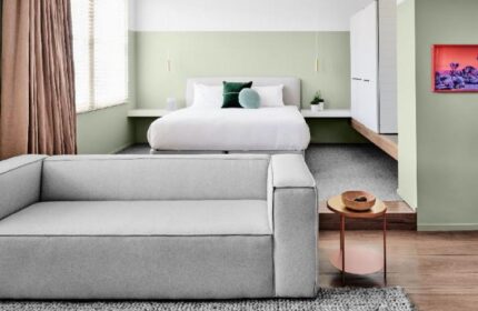 The Prince Hotel room interior. Modern design, white bed, gray couch, and minimalist decor. Gay-friendly hotel, comfortable and stylish.