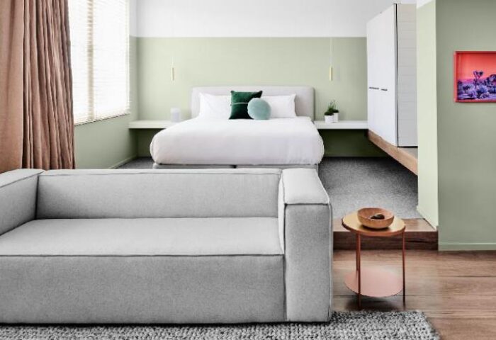 The Prince Hotel room interior. Modern design, white bed, gray couch, and minimalist decor. Gay-friendly hotel, comfortable and stylish.