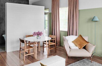 The Prince Hotel interior. Gay-friendly hotel room with dining table, chairs, pink curtains, and a comfortable armchair. Modern design.