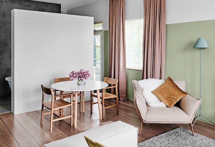 The Prince Hotel interior. Gay-friendly hotel room with dining table, chairs, pink curtains, and a comfortable armchair. Modern design.
