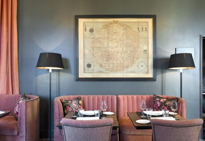 Elegant dining area at The Principal Madrid Hotel, a gay-friendly hotel. Pink booths, map art, and stylish lamps. Ideal for gay travel in Madrid.