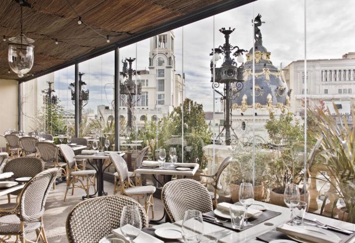 Rooftop dining at The Principal Madrid Hotel, a gay-friendly hotel. Views of Madrid's skyline from the restaurant. Tables set for service.