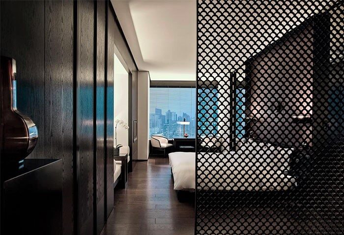 The PuLi Hotel and Spa's interior. A gay-friendly hotel with a modern room design, dark wood accents, and a view of the city skyline.