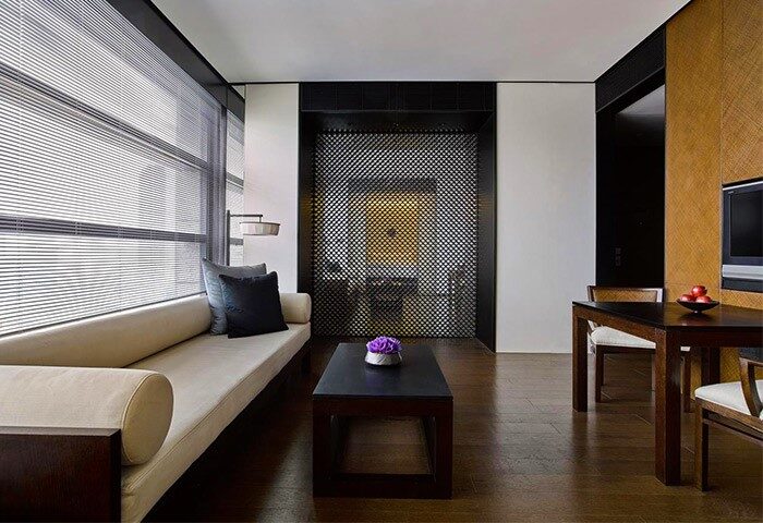 The PuLi Hotel and Spa's gay-friendly suite: Living area with couch, table, and decorative screen. Upscale design for gay travelers.