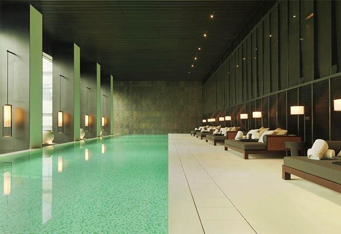 Indoor pool at The PuLi Hotel and Spa, a gay-friendly hotel. Loungers line the pool's edge. Modern design, relaxing atmosphere. Shanghai travel.