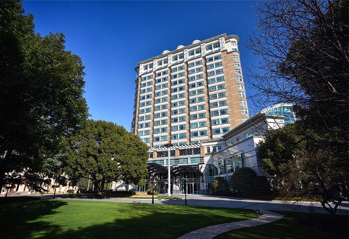 Radisson Collection Hotel Xing Guo Shanghai exterior. Gay-friendly hotel with a tall building, green lawn, and trees. Shanghai travel.