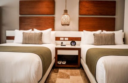 The Reef 28 Hotel & Spa All Suites room. Luxury adults-only, all-inclusive optional, gay-friendly hotel room with two beds and nightstand.