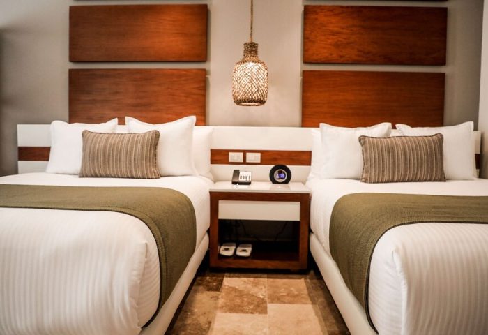 The Reef 28 Hotel & Spa All Suites room. Luxury adults-only, all-inclusive optional, gay-friendly hotel room with two beds and nightstand.