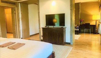The Rim Chiang Mai Hotel's gay-friendly room. A bed with towels, a TV, and a desk are visible. Luxury gay travel in Thailand.
