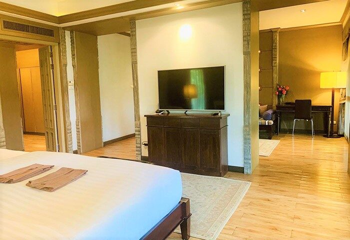 The Rim Chiang Mai Hotel's gay-friendly room. A bed with towels, a TV, and a desk are visible. Luxury gay travel in Thailand.