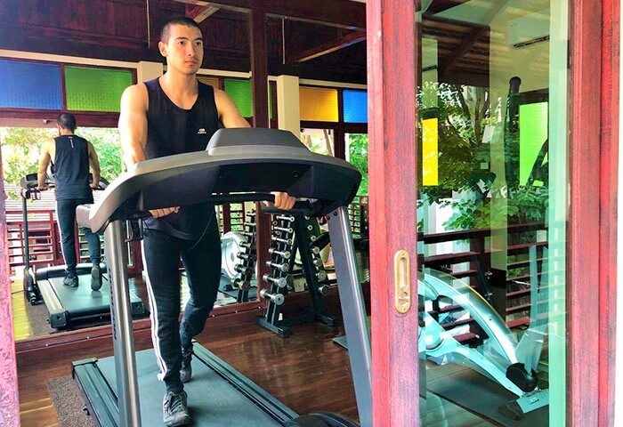Gay-Friendly The Rim Chiang Mai Hotel gym. Man on treadmill. Fitness center at this gay travel destination in Thailand. Weights visible.