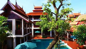 The Rim Chiang Mai Hotel pool area. Gay-friendly hotel with traditional Thai architecture, pool, umbrellas, and lush greenery. Great for gay travel.