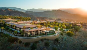 The Ritz-Carlton, Rancho Mirage: Gay-friendly hotel aerial view. Resort with mountains, palm trees, and desert landscape at sunset.