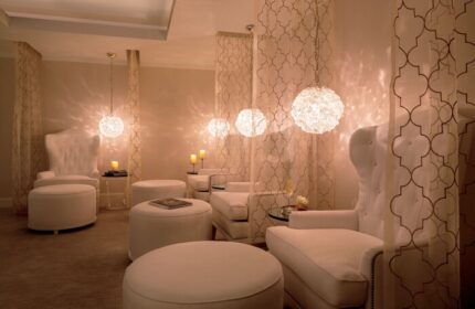 The Ritz-Carlton Rancho Mirage gay-friendly hotel spa. White lounge chairs and ottomans under decorative lights and curtains. Relaxing space.