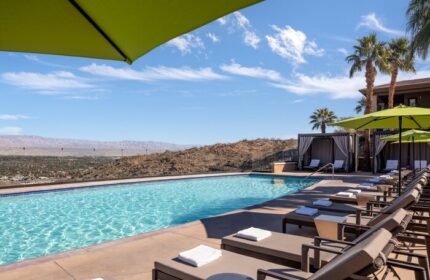 Pool view at The Ritz-Carlton, Rancho Mirage, a gay-friendly hotel. Lounge chairs, umbrellas, and cabanas offer relaxation with desert views.