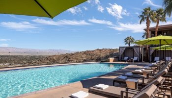 Pool view at The Ritz-Carlton, Rancho Mirage, a gay-friendly hotel. Lounge chairs, umbrellas, and cabanas offer relaxation with desert views.