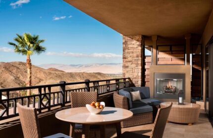 The Ritz-Carlton, Rancho Mirage gay-friendly hotel balcony view. Outdoor seating, fireplace, desert landscape. Ideal for gay men's travel.