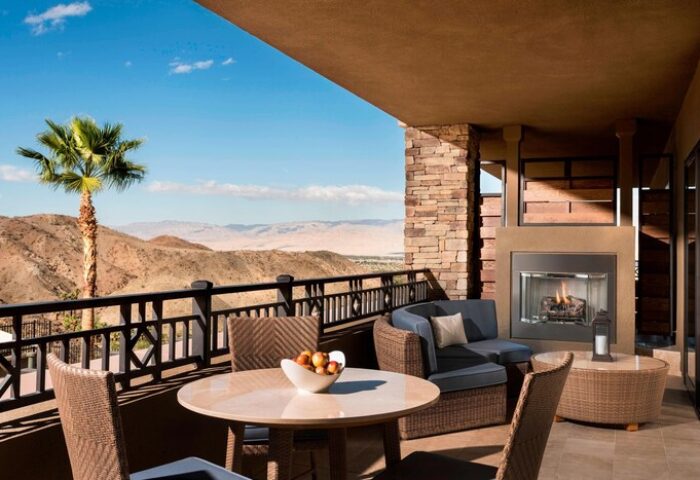 The Ritz-Carlton, Rancho Mirage gay-friendly hotel balcony view. Outdoor seating, fireplace, desert landscape. Ideal for gay men's travel.