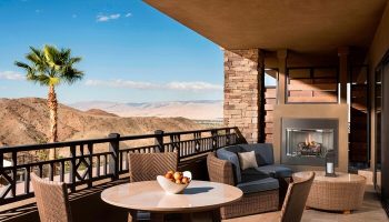 The Ritz-Carlton, Rancho Mirage gay-friendly hotel balcony view. Outdoor seating, fireplace, desert landscape. Ideal for gay men's travel.