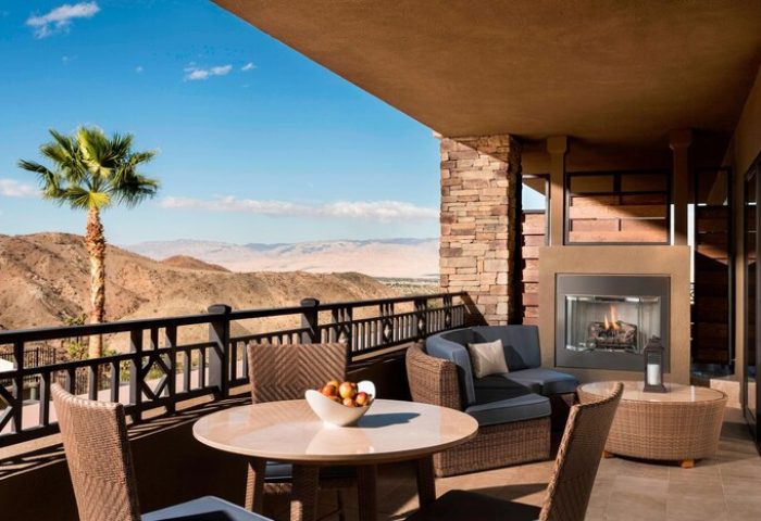 The Ritz-Carlton, Rancho Mirage gay-friendly hotel balcony view. Outdoor seating, fireplace, desert landscape. Ideal for gay men's travel.
