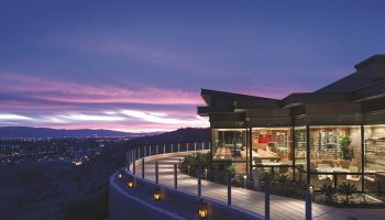 The Ritz-Carlton, Rancho Mirage: A gay-friendly hotel at dusk. View of the restaurant, walkway, and city lights. Luxury gay travel.