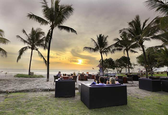 Sunset at The Royal Beach Seminyak Bali, MGallery Collection. Gay-friendly hotel with beachside dining, palm trees, and relaxed atmosphere.