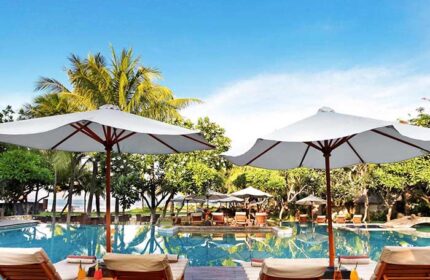 Pool view at The Royal Beach Seminyak Bali, MGallery Collection. Gay-friendly hotel with umbrellas and lounge chairs for a relaxing vacation.