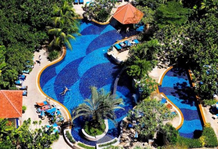 Aerial view of The Royal Paradise Hotel & Spa's pool. Gay-friendly hotel with lush greenery, blue water, and relaxing lounge chairs.