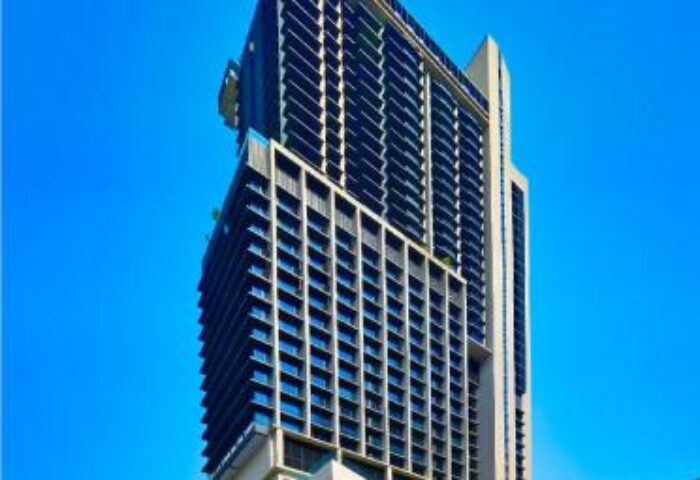 The RuMa Hotel and Residences exterior, a gay-friendly hotel in Kuala Lumpur. Modern architecture against a bright blue sky. Luxury travel.