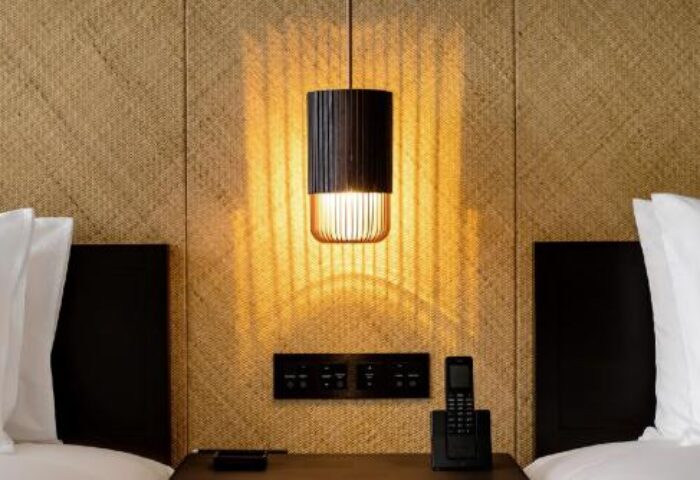 The RuMa Hotel and Residences bedroom detail. Bedside lamp, headboard, and pillows. Gay-friendly hotel room interior.
