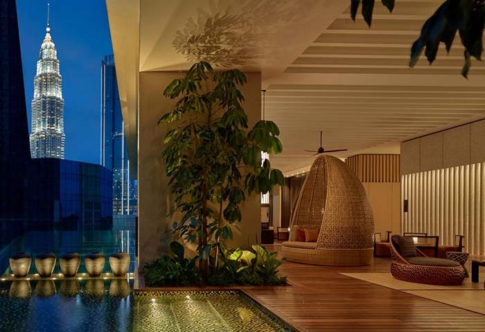 The RuMa Hotel and Residences' pool area at dusk. Gay-friendly hotel with Petronas Towers view. Luxury travel for gay men in Kuala Lumpur.