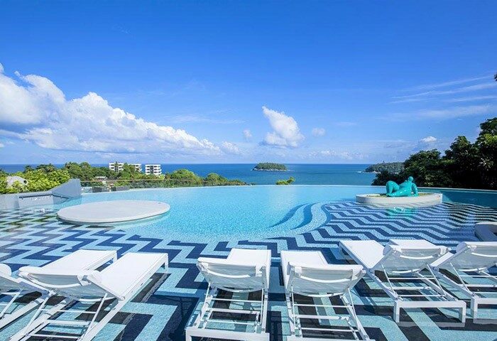 Infinity pool at The SIS Kata Resort, a gay-friendly hotel. Ocean view, lounge chairs, & blue statue. Perfect for gay travel.