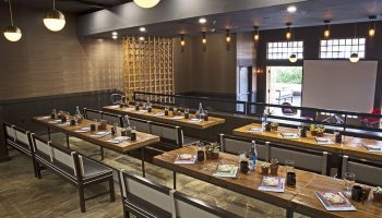 The Saguaro Palm Springs gay-friendly hotel event space. Long tables with benches, set for a meeting. Stylish, modern design.