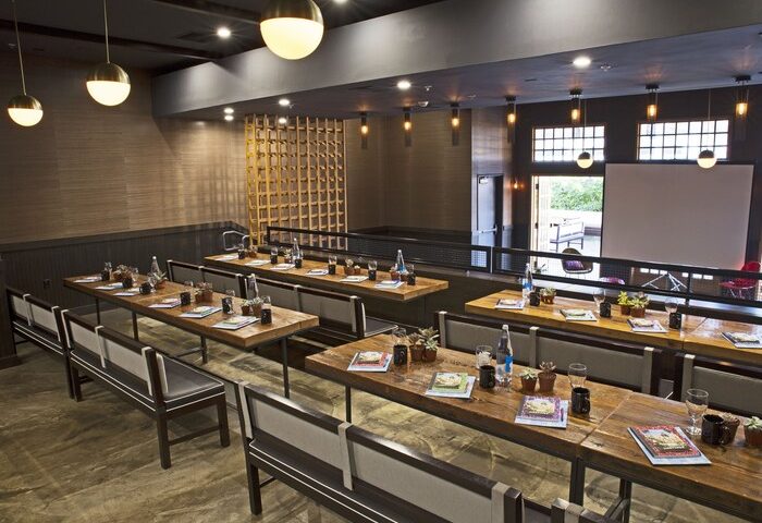 The Saguaro Palm Springs gay-friendly hotel event space. Long tables with benches, set for a meeting. Stylish, modern design.