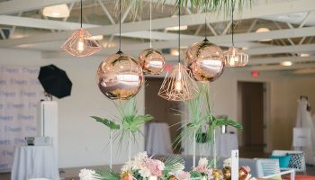 Gay-Friendly Hotel The Saguaro Palm Springs: Stylish event space with pink table, white chairs, palm fronds, and copper pendant lights.