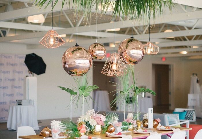 Gay-Friendly Hotel The Saguaro Palm Springs: Stylish event space with pink table, white chairs, palm fronds, and copper pendant lights.
