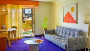 The Saguaro Palm Springs gay-friendly hotel room. Colorful interior with sofa, table, and balcony view. A vibrant Palm Springs stay awaits!
