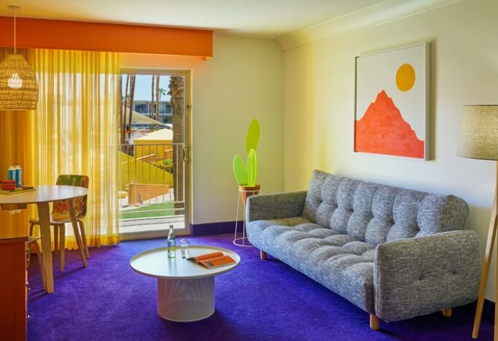 The Saguaro Palm Springs gay-friendly hotel room. Colorful interior with sofa, table, and balcony view. A vibrant Palm Springs stay awaits!