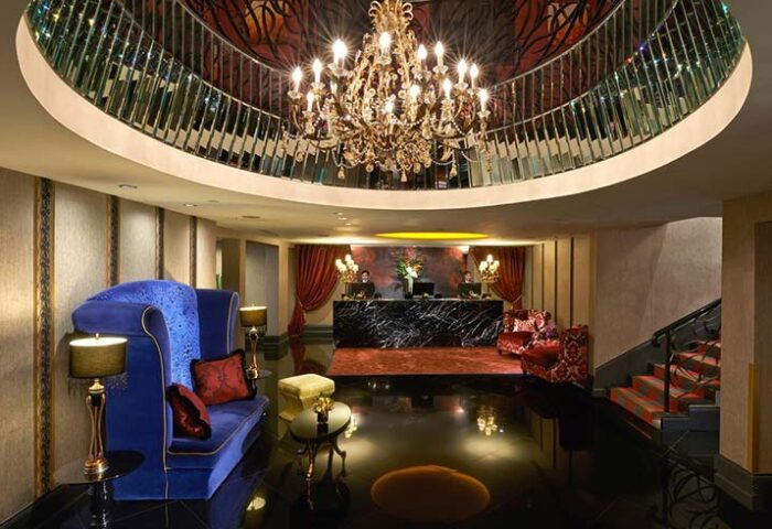 The Scarlet Singapore Hotel lobby. Gay-friendly hotel with chandelier, marble reception desk, and plush seating. Upscale interior design.