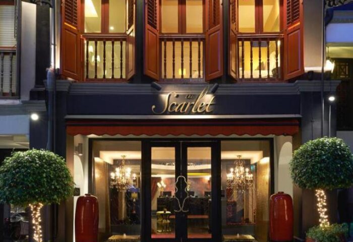 Facade of The Scarlet Singapore Hotel, a gay-friendly hotel. The entrance has glass doors and windows with a chandelier visible inside.