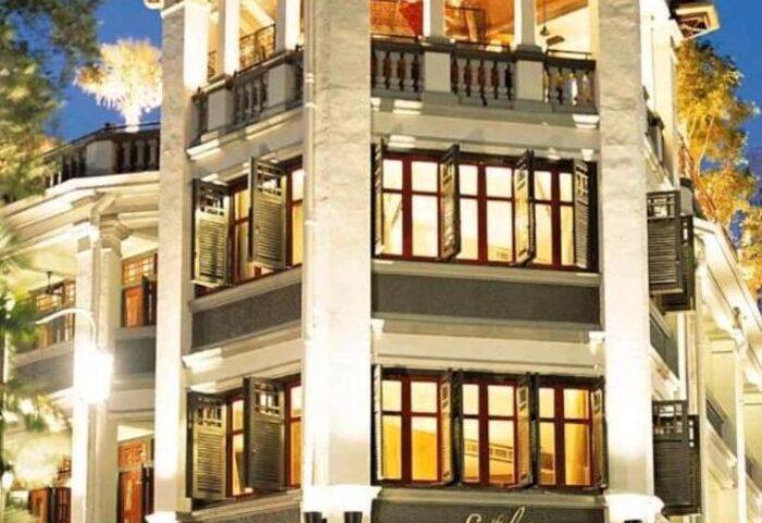 Facade of The Scarlet Singapore Hotel, a gay-friendly hotel with white pillars and open shuttered windows. Great for gay travel.